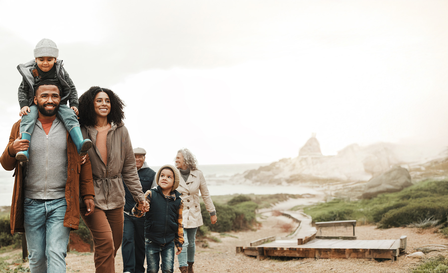 Family at the beach. A man carries a child on his shoulders.
